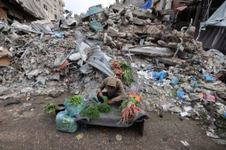 عکسهای جالب,عکسهای جذاب,یک جوان فلسطینی در شهر رفح در جنوبی ترین نقطه نوار غزه، در آستانه عید فطر، در مقابل ساختمانی که در اثر حملات اسراییل ویران شده است، سبزیجات می فروشد.